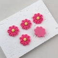 Detailed view of five pink resin flower charms with yellow centers on white stone - Rose Red