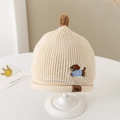 Close-up of baby knit beanie with cute puppy embroidery and soft pom-pom detail - 1-3 Years / Off White
