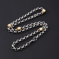Macro detail of silver and gold stainless steel Cuban chain necklace on black backdrop - 6mm Round Rolo Chain With Gold Beads Necklace
