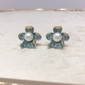Macro shot of blue flower earrings with a white pearl center and golden edges - Blue