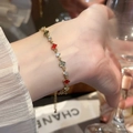 Detalle de una pulsera de trébol dorada con esmalte rojo y circón en la muñeca - 2# Pulsera Trébol Rojo (Chapado en Oro Real)