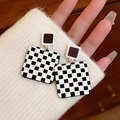 Checkered black and white square earrings held by hand over a white sweater cuff - 35# Silver Needle - Square Checkerboard