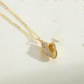 Macro del ciondolo a conchiglia dorata con zirconi su collana di perle sobria - Conchiglia