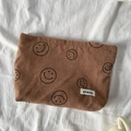 Detail of a brown corduroy bag featuring black smile patterns and a woven logo label - Brown Smiley Face Storage Bag
