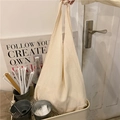 Close-up of cream canvas tote bag showing the textured fabric and knotted handle detail - Beige