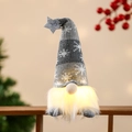 Nahaufnahme eines leuchtenden Weihnachtswichtels mit Sternhut und Schneeflocken - Sitzende Haltung / Grau