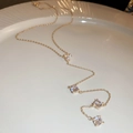 Close-up of golden Y-shaped necklace with drop zircons on a white ceramic plate - Gold
