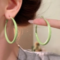 Detail of light green enamel hoop earrings showing texture and size on a model - Green-Large