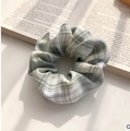 Green and white checkered organza scrunchie hair tie on a decorative book background - Blue Green Fabric Plaid