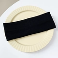 Detail view of a wide black ribbed knit headband on a minimalist white ceramic tray - Black
