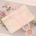 Dettaglio della collana di perle d'argilla rosa con cuore rosso e perle bianche - Rosa