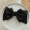 Elegant black satin bow hair clip for girls, showcased on a white ceramic plate - Black