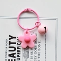 Detailed view of a pink knit flower and bell keychain on a minimalist white display card - Pink
