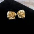 Primo piano di orecchini a forma di rosa dorata con petali in rilievo su velluto nero - Stile Rosa in Rilievo / Orecchini ad Ago in Argento-Oro