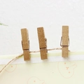 Three decorative golden wooden photo clips on a natural jute rope with cartoon paper - Gold