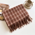 Detail of plaid scarf with tassels, orange and brown knit texture on a lifestyle setting - Beige and Orange
