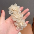 Elegant champagne camellia hair clip with mesh flowers and pearls held in hand - Spring Clips / Beige Mesh Stamen Style