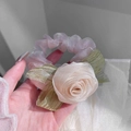 Close-up of soft pink organza rose scrunchie with green leaf detail held in hand - Champagne