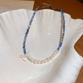 Détail du collier de perles bleu blanc avec pendentif papillon dans un plat coquillage - Collier de perles papillon bleu (38# Collier)