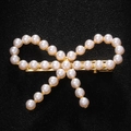 Macro shot of gold-finished bow hair clip with elegant white pearls and rhinestones - Pearl Gold