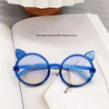 Detailed view of blue glitter cat-ear children sunglasses with gradient lenses on a magazine - Blue