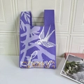Detail of a purple knitted tote bag featuring a white swallow and Spring text design - Spring Swallow Purple