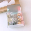 Macro detail of baby hair ties in pastel colors stored in a transparent Jewel Box case - Light Multicolor Style