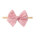 Detail of pink lace hollow bow hairband on a beige elastic nylon band for infants - Pink