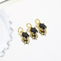 Detailed macro view of three golden oval charms with black stones for jewelry making - Black