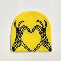 Close-up of a bright yellow knitted beanie featuring black skull hands heart pattern - Yellow and Black