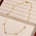 Close-up of gold chain necklace with five purple gemstone flower pendants in jewelry box - Purple Flower - Gold