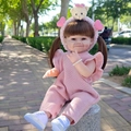 55cm lifelike reborn doll in pink knit romper sitting outdoors on a stone path - Pink Knit Romper Smiling Face / Doll Clothes (Outfit Only)