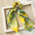 Detail of satin ponytail scrunchie with yellow and green tropical leaf print on wood frame - Yellow Leaf Ribbon