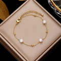Golden stainless steel pearl bracelet displayed on elegant champagne silk jewelry box - Gold Chain with 3 Pearl Accents