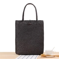 Deep brown woven straw tote bag with wooden button closure on light wooden desk - Black
