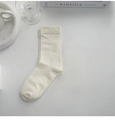 Minimalistische Baumwollsocken in Cremeweiß flach auf weißem Untergrund liegend - Creme