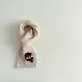 Detalle de bufanda infantil de punto crema con tierno parche de oso pardo en relieve - Beige