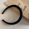 Detail of a thick black knitted headband featuring a handmade label on the inner side - Black