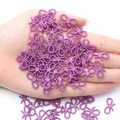 Handheld view of small purple pearlescent resin bow charms for DIY craft accessories - Dark Purple