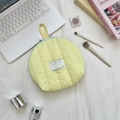 Close-up of a soft quilted shell makeup bag with a top handle and zip closure - Yellow