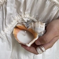 Natural conch shell scented candle in white held by a hand on beige fabric background - Stone Conch Candle [10-12cm] / Freesia [Boxed]