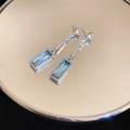 Detail of silver drop earrings featuring a blue rectangular gemstone on a mirror - Silver Pin Blue Rhinestone Square Earrings