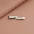Dettaglio del fermacravatta in argento con incisione Best Man su sfondo rosa a trama - Best Man