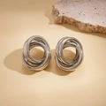 Close-up of silver geometric multi-layer intertwined loop earrings on textured stone - Silver