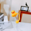 Dettaglio di un copri cannuccia in silicone a forma di papera gialla con cappuccio - Tappo per cannuccia anatroccolo