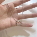 Close-up of a silver hollow heart-shaped pendant on a fine snake chain necklace - Silver (XL8022Y)
