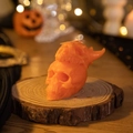 Bright orange stacked skull scented candle on wood slice for Halloween decor - Horned Skull / Orange