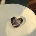 Detailed close-up of a heart-shaped acetate hair clip with tortoiseshell pattern on ceramic - Black Gold Tortoise