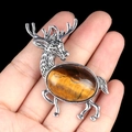 Silver-tone elk brooch pendant with oval tiger eye stone inlay shown in hand - Tiger's Eye