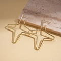 Vista macro de pendientes dorados minimalistas con forma de estrella sobre base de piedra - Dorado